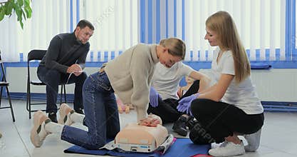 Woman demonstrating CPR on mannequin in first aid class.