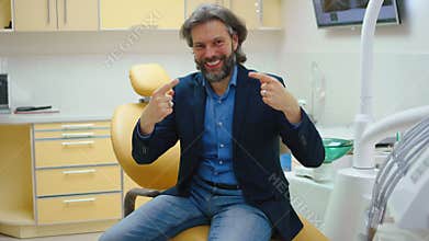Perfect smile patient man at the dentist happy and excited after the oral care treatment he looking to the camera am