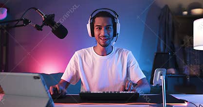 Asian man playing online computer video game, colorful lighting broadcast streaming live at home. Ecstatic celebration winning