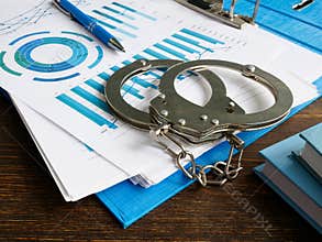 Financial crime concept. Handcuffs and folder with audit report.