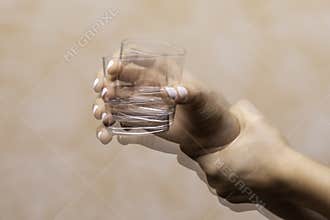 hand holding drinking glass suffering from Parkinson& x27;s disease