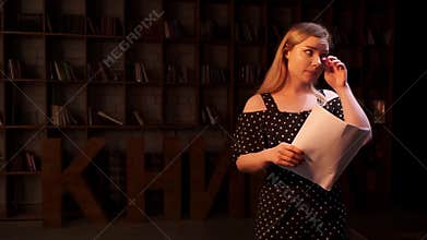 Sad young actress is crying during break of repetition and waving herself by sheets of paper