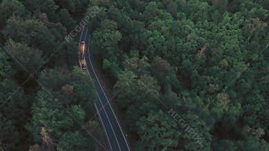 Aerial footage of cars on a forest road at dusk
