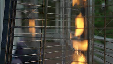 Burning fire in a gas outdoor heater working on terrace. Steel metal pyramid.