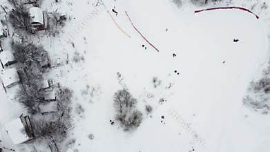 Happy families go down the hill in a snowy winter park, aerial view from a drone