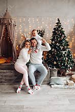 Delighted couple and lovely child posing near Christmas tree