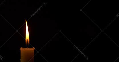 Closeup burning single candle flame isolated on black background