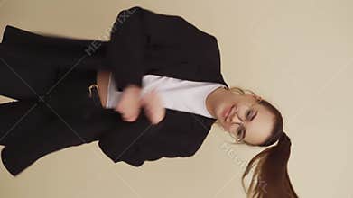 Beautiful young woman dances on beige background.