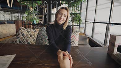 First-person view. The man gently holds the woman&#x27;s hand. The beautiful blonde is not on a first date.
