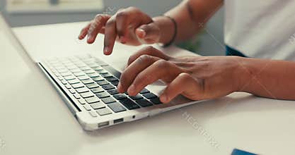 Close-up of silver latop standing on white desk, dark-skinned man working on it, young hands, typing text into keyboard