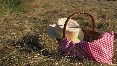 Vintage picnic basket and straw hat with red gingham blanket shot in rural field