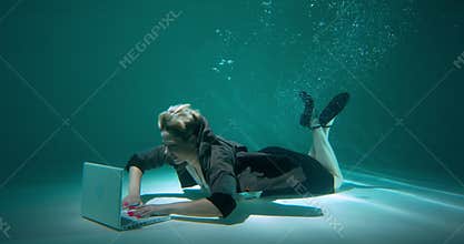Beautiful happy young determined manager business woman dives underwater to work with laptop, cinematic slow motion.