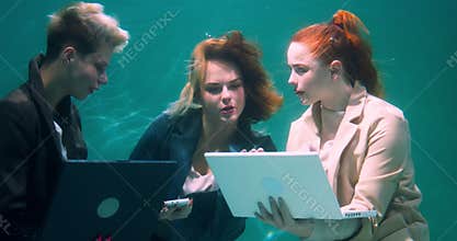 BRAINSTORMING CONCEPT Amazing underwater shot of three young business women using laptops working together slow motion.