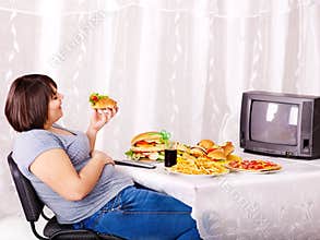 Woman eating fast food and watching TV.