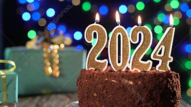 Happy New Year. golden candle number two thousand twenty four on a sweet cake on the table, 2024. Fire from a lighter