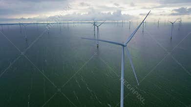 Aerial video. Enormous windmills stand in the sea along dutch Ijsselmeer by stormy and rainy day.