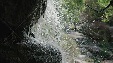 A waterfall on the rocks, the splash of water over the stones, a mountain river flows down the stone, beautiful drops, splashes