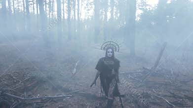 Woman in image of witch walks across dark and foggy forest