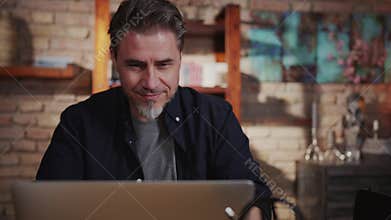 Happy older man working at home on laptop in home office
