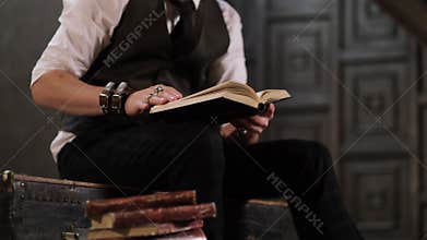 Stylishly dressed man leafing through vintage books in an old dark library. close up view. Slow motionnvideo. stock