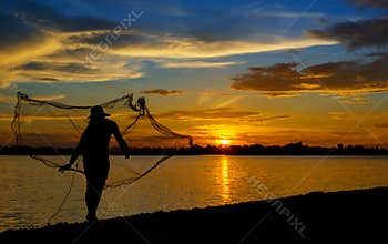 Silhouette of Thai Fisherman catching the fish in twilight  Beautiful Sunset in the sky with sky blue and orange light of the sun