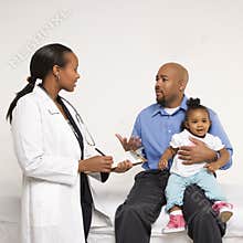 Father holding baby talking to pediatrician.