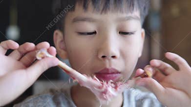 4k Young boy try to taking a a meet from a bone to eat