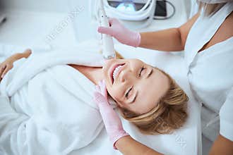 Young female client enjoying the microneedling procedure