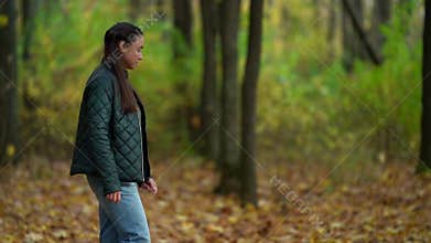 Adult brunette lady is walking alone in picturesque autumn forest, calm and inspiring strolling at nature