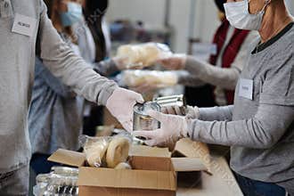 Group of volunteers in community donation center, food bank and coronavirus concept.