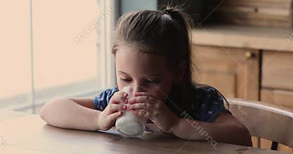 Little girl sit at table drinking milk beverage