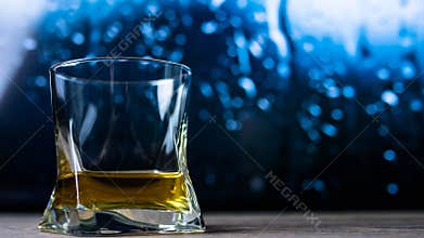 A glass of cognac, brandy, whiskey against a background of drops, whiskey in a glass close-up, against a background of bokeh.