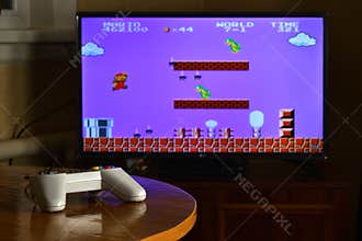 KHARKOV, UKRAINE - NOVEMBER 12, 2020: Dendy video game controller on table with Super Mario Bros game on display