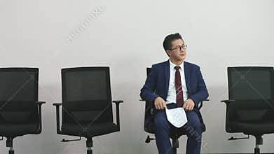 Older asian corporate executive waiting in chair for job interview