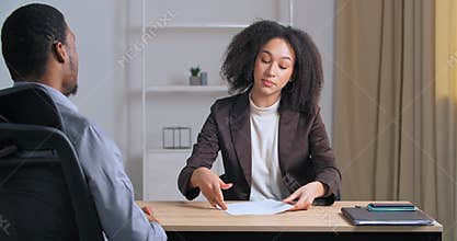 Two colleagues sitting in office meeting, Afro American business woman giving report to boss businessman finds error