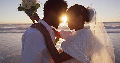African american couple in love getting married, looking at each other on the beach at sunset