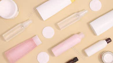 Wellness spa beauty products with towels move on left and right side on beige background with copy space. Stop motion flat lay