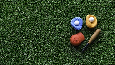 A miniature toy baseball equipment of cap,ball,glove and bat on green grass background with copy space