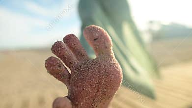Close-up of foot and toes in the sand of a young girl in slow motion. Wiggles toes on a sandy beach on a sunny day