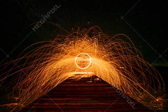 Fire dancing show swing lighting effects circle on bridge dark sky on night time.