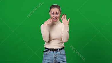 Reaction of excited young woman on green screen. Portrait of beautiful slim Caucasian lady shaking hands with tears of
