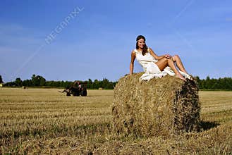 Girl in a rural clothing sitting on the haystack