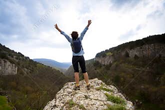 Woman on top of the mountain reaches for the sun