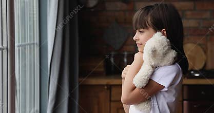 Upset lonely little girl hug stuffed toy look into distance
