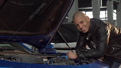 Cheerful handsome African man smiling to the camera while working at his garage