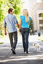 Couple walking dog in city street