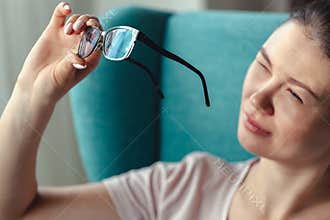 Young woman cleaning glasses with a napkin while sitting 