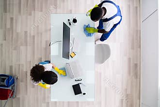 Male And Female Cleaners Cleaning Office Table