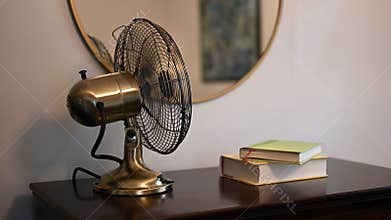 Vintage table fan with mirror and stack of books