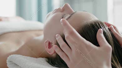 Specialist massages head of tranquil woman client on couch